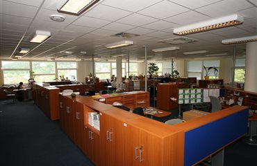 Tady jsme již o patro níže v otevřených kancelářích. Jsou zde speciální koberce ze čtverců (aby šly vyměnit v případě polití kávou) a speciální zvukopohltivé podhledy, které umravňují hukot mluvících lidí. Každé pracoviště má vytvořen perfektní pracovní prostor. Thubnail
